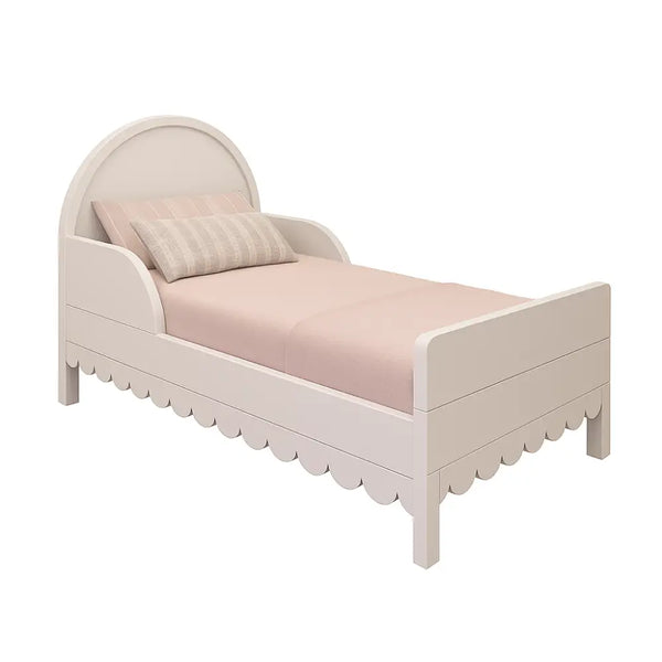 The Petal Bed by Baby Belle in single size — white children’s bed with scalloped edges, curved headboard, and soft pastel bedding on a plain white background