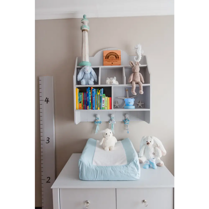 Grey Lyra wall shelf with open cubbies, pigeon holes, tongue-and-groove detail and three rounded hooks, styled for nursery or kids’ room
