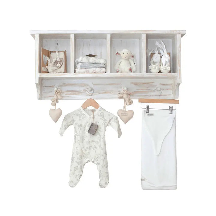 Distressed white Orchid wall shelf with four cubbies and three hooks, styled with baby clothes and toys, ideal for nursery storage
