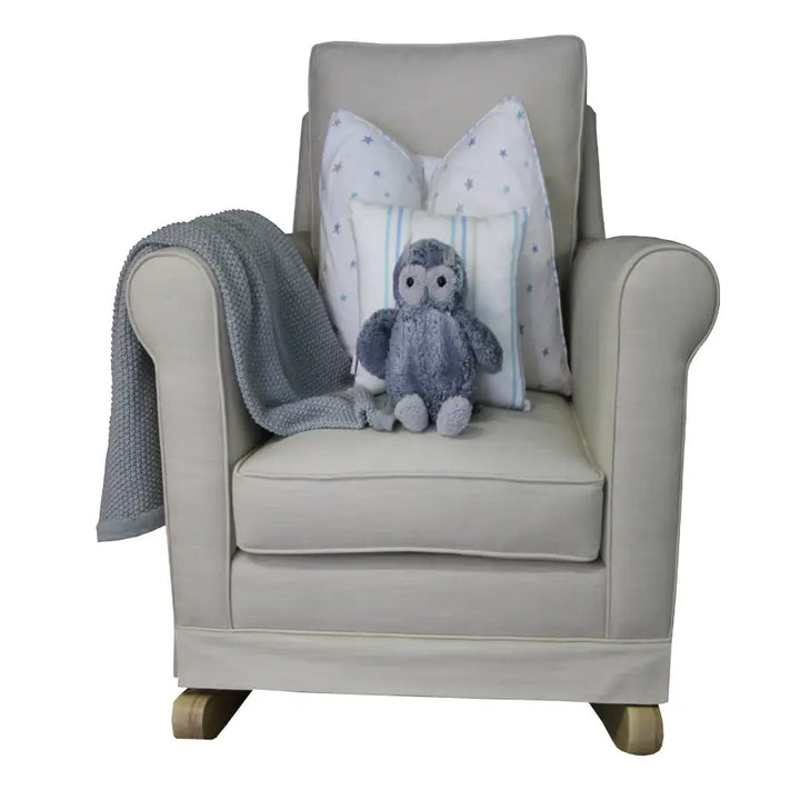 Tres Chic Rocking Chair in sand fabric with natural oak rocking legs, styled with grey throw, star-print cushions, and a soft owl plush toy.