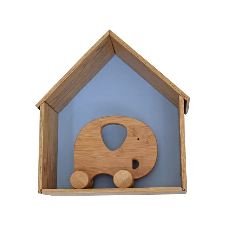 Small Sebastian house-shaped wall shelf crafted from solid French Oak with blue painted back panel, styled with a wooden elephant toy – ideal for nursery or kids’ room décor
