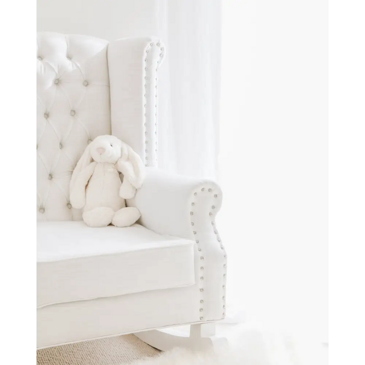 Close-up of the Baby Belle Ava Rocking Chair in white linen with diamond buttoning, studded armrest detail, and solid wood rocking base – styled in Jenna McArthur’s nursery