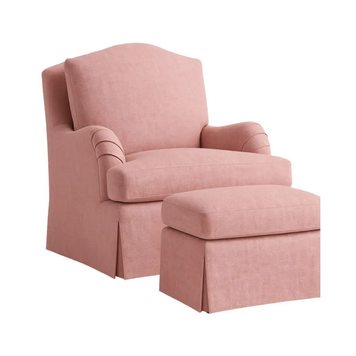 The Balmoral Chair, upholstered in a blush pink fibregaurd fabric, featuring a high back, pleated arms, deep seat cushion, and a tailored skirted base.