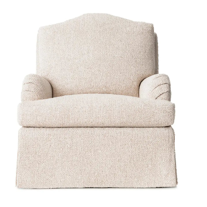 The Balmoral Chair, upholstered in a cream textured woven fabric, featuring a high back, pleated arms, deep seat cushion, and a tailored skirted base.