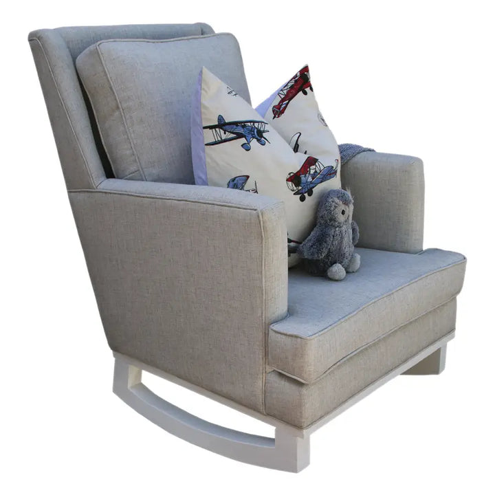 Mist Jayden rocking chair with a soft grey fabric, paired with a playful airplane-print pillow, a cozy knit throw, and a small plush owl placed on the seat.