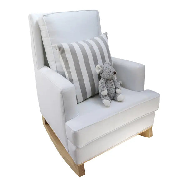 White Jayden rocking chair with natural wood base, featuring plush cushions, a striped accent pillow, and a soft grey stuffed animal placed on the seat.