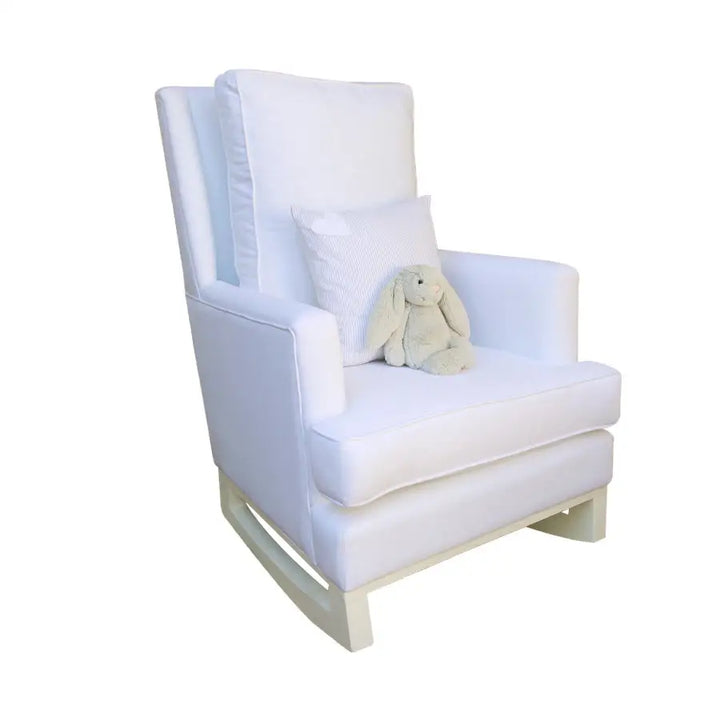 White Jayden rocking chair with natural wood base, featuring plush cushions, a striped accent pillow, and a soft grey stuffed animal placed on the seat.