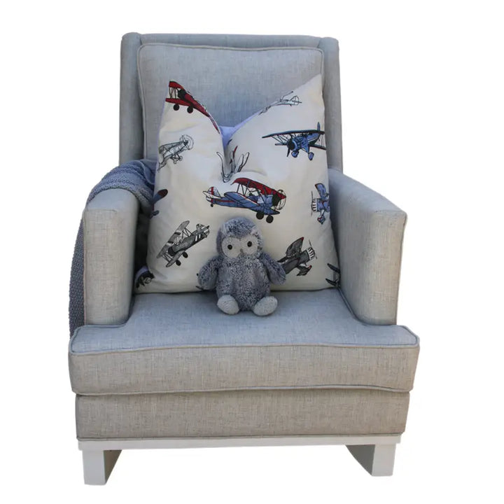 Mist Jayden rocking chair with a soft grey fabric, paired with a playful airplane-print pillow, a cozy knit throw, and a small plush owl placed on the seat.