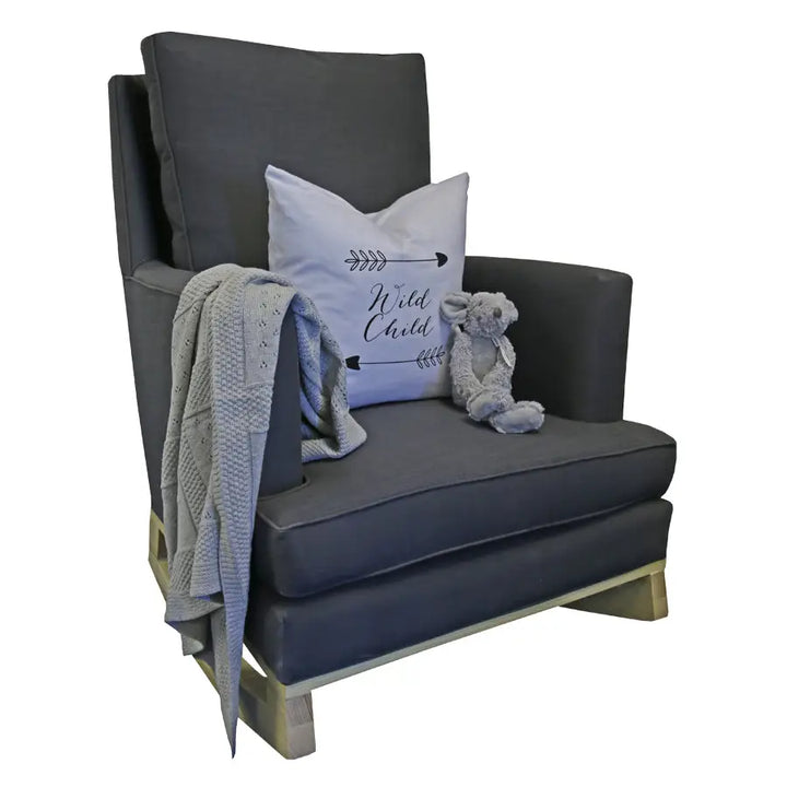 Charcoal Jayden rocking chair with deep grey upholstery, styled with a "Wild Child" accent pillow, a knitted throw draped over the arm, and a plush bunny toy on the seat.
